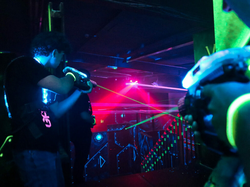 Jungs schießen aus der Deckung mit Lasertag Pistolen